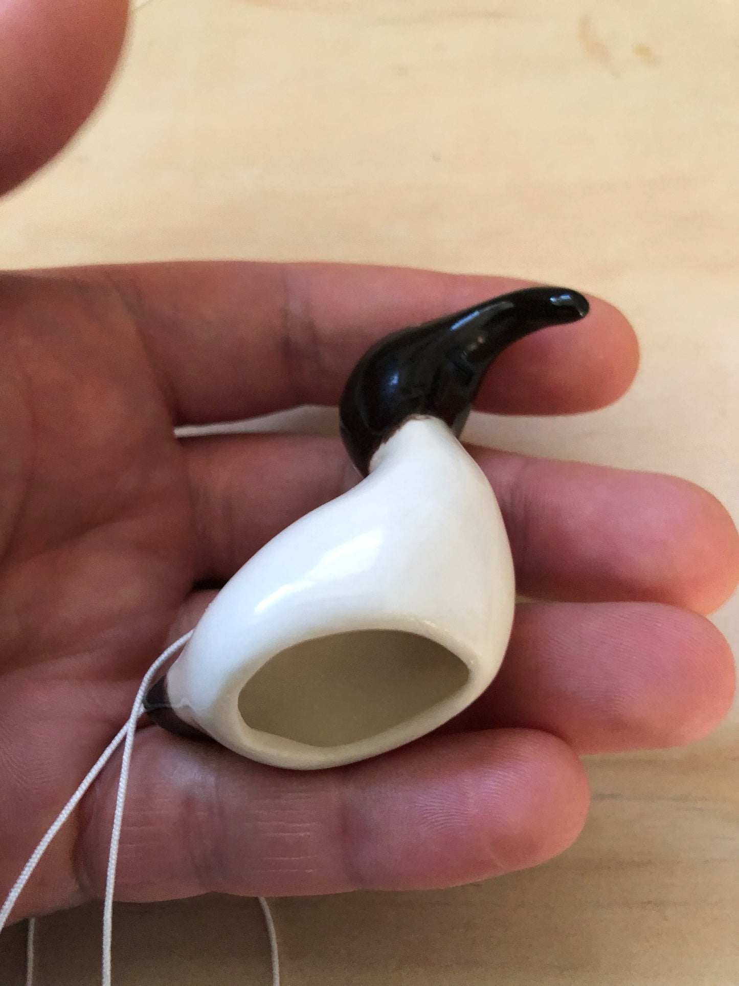 A person holding a ceramic Australian White Ibis decoration in their hand to demonstrate its size, highlighting the bird's distinctive features such as its long curved beak and black head.
