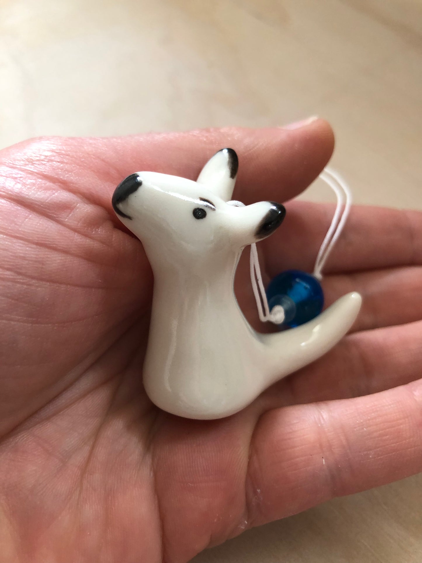 Side view of a ceramic kangaroo ornament cradled in a hand, highlighting its natural charm and the beauty of ceramic craftsmanship, ideal for showcasing the ornament's profile.