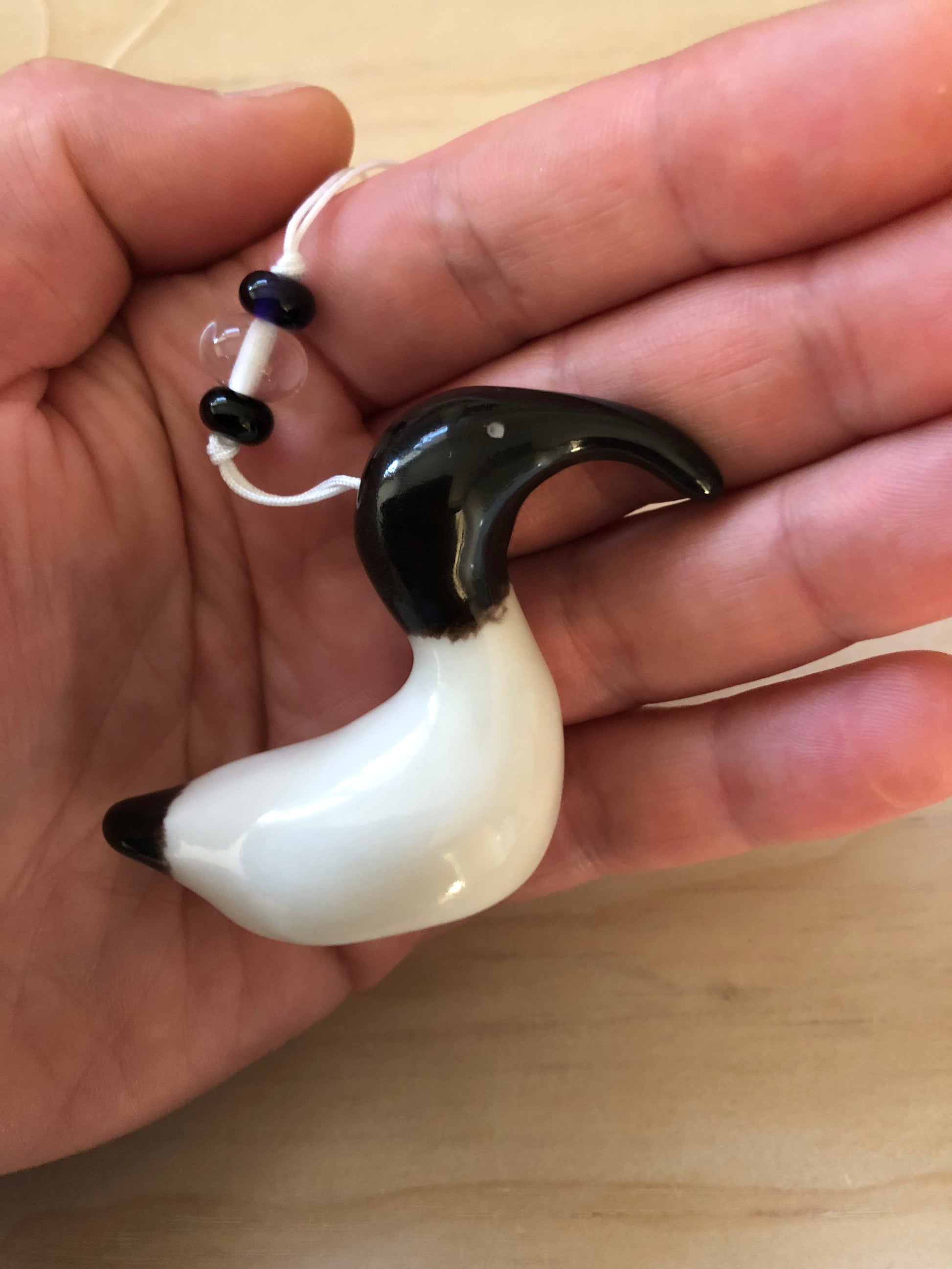 Ceramic decoration of an Australian White Ibis held in a person's hand for size comparison, featuring the bird's characteristic black head and long beak.