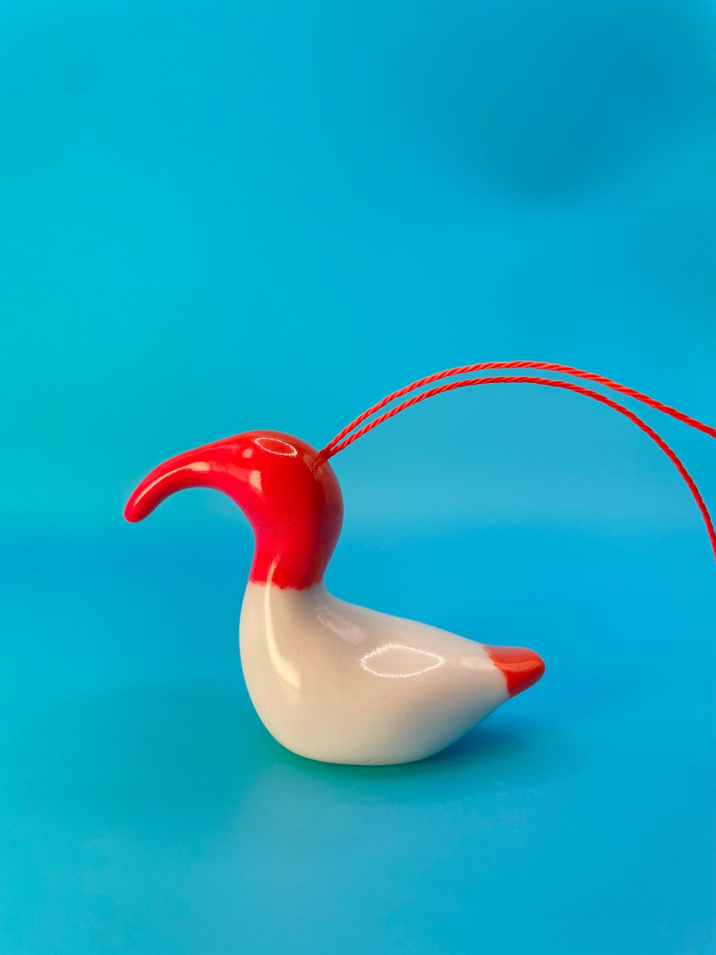 Vibrant red ceramic decoration of an Australian White Ibis, affectionately known as a 'bin chicken,' featuring its distinctive curved beak and textured body.