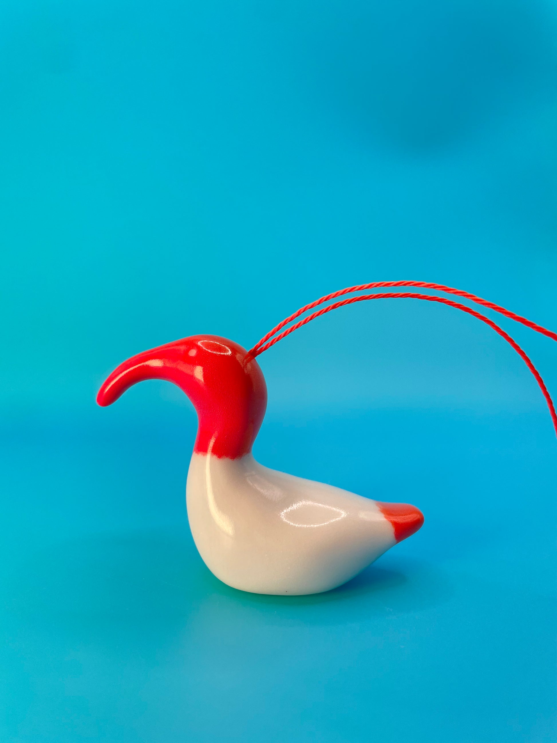 Vibrant red ceramic decoration of an Australian White Ibis, affectionately known as a 'bin chicken,' featuring its distinctive curved beak and textured body.