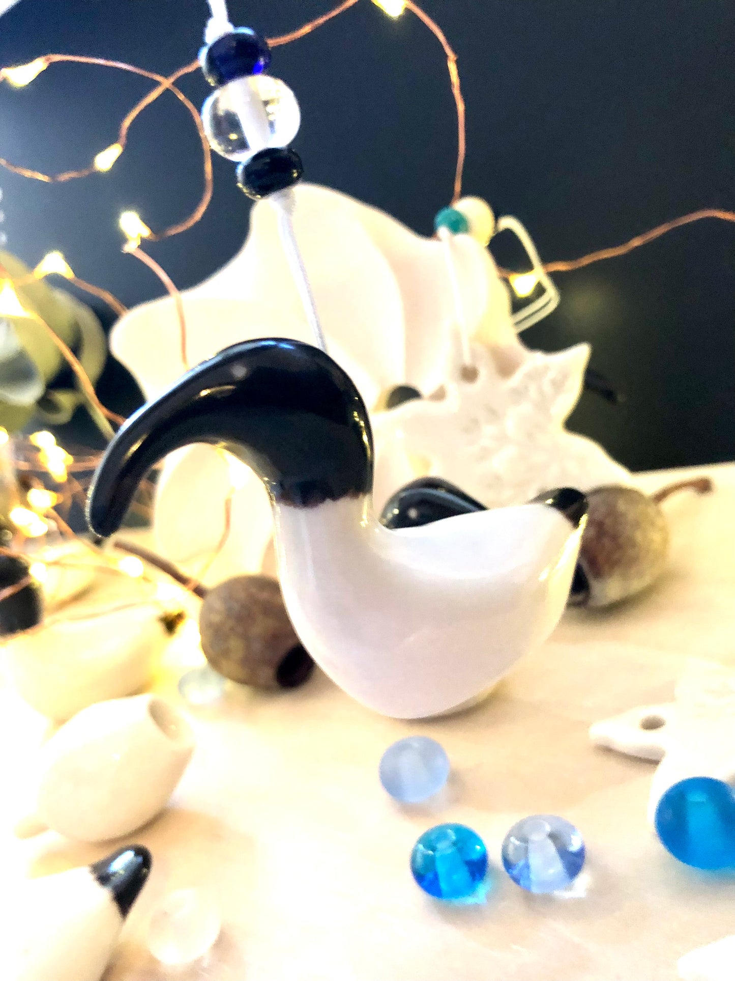 Porcelain chicken ornament, handcrafted with care, hanging on a Christmas tree with beads and lights, emphasising the beauty of handmade decorations and the joy of the holiday season.