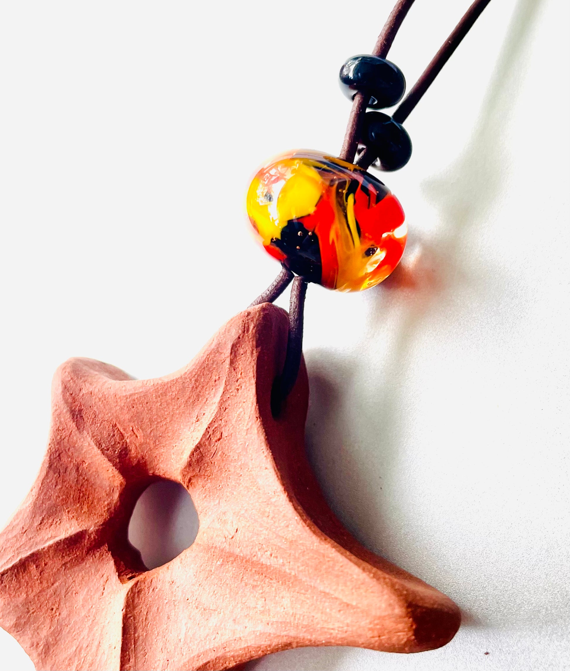Detailed close-up of a ceramic star pendant, hand-carved with precision and complemented by glass beads, highlighting the beauty of ceramic craftsmanship and the shine of glass.