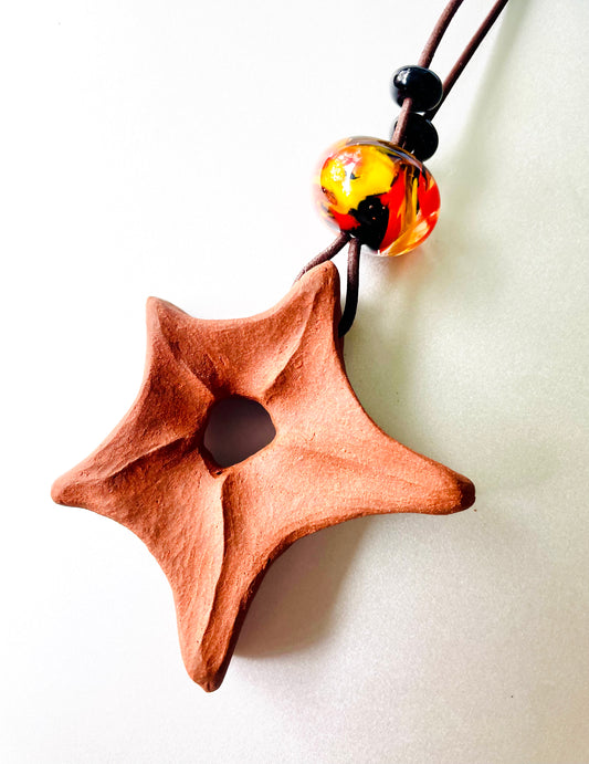 Hand-carved ceramic star pendant, adorned with glass beads, showcasing a blend of artisanal craftsmanship and elegant design, perfect for adding a touch of handmade charm to any outfit.