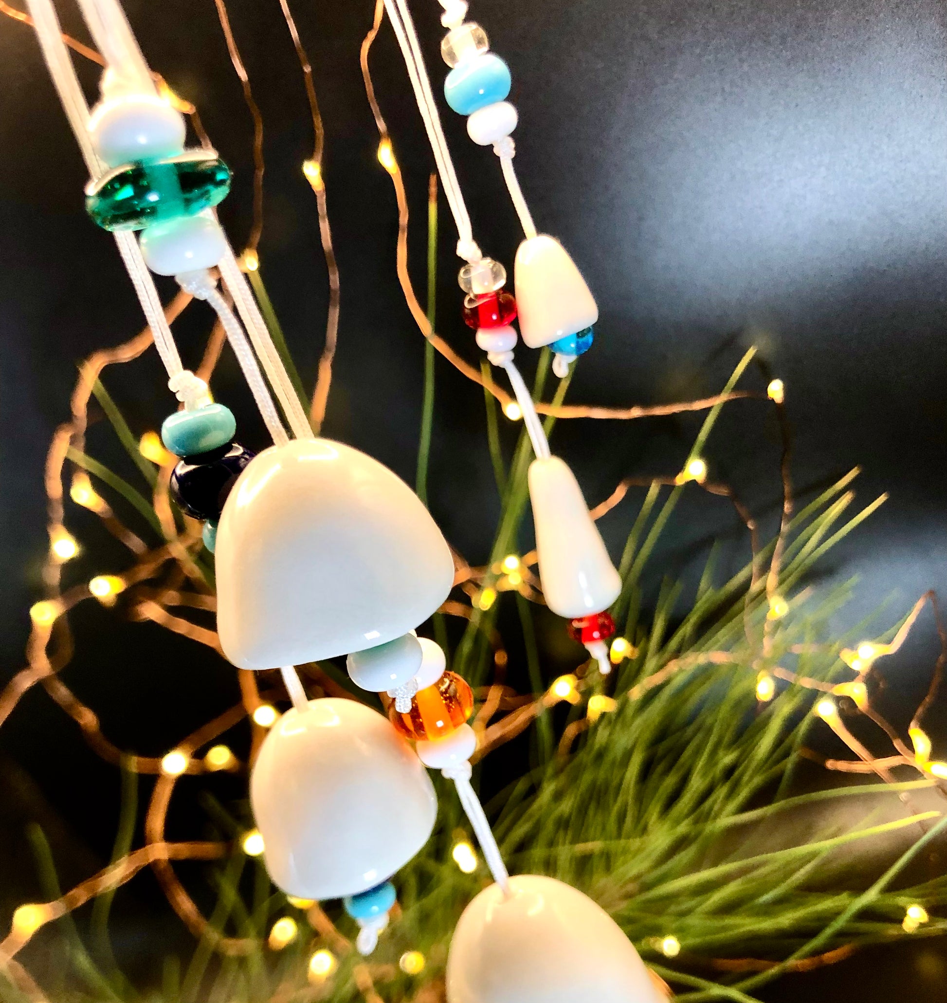 Christmas tree decorated with ceramic bells, adorned with beads, and illuminated by twinkling lights, showcasing a blend of handmade craftsmanship and festive cheer.