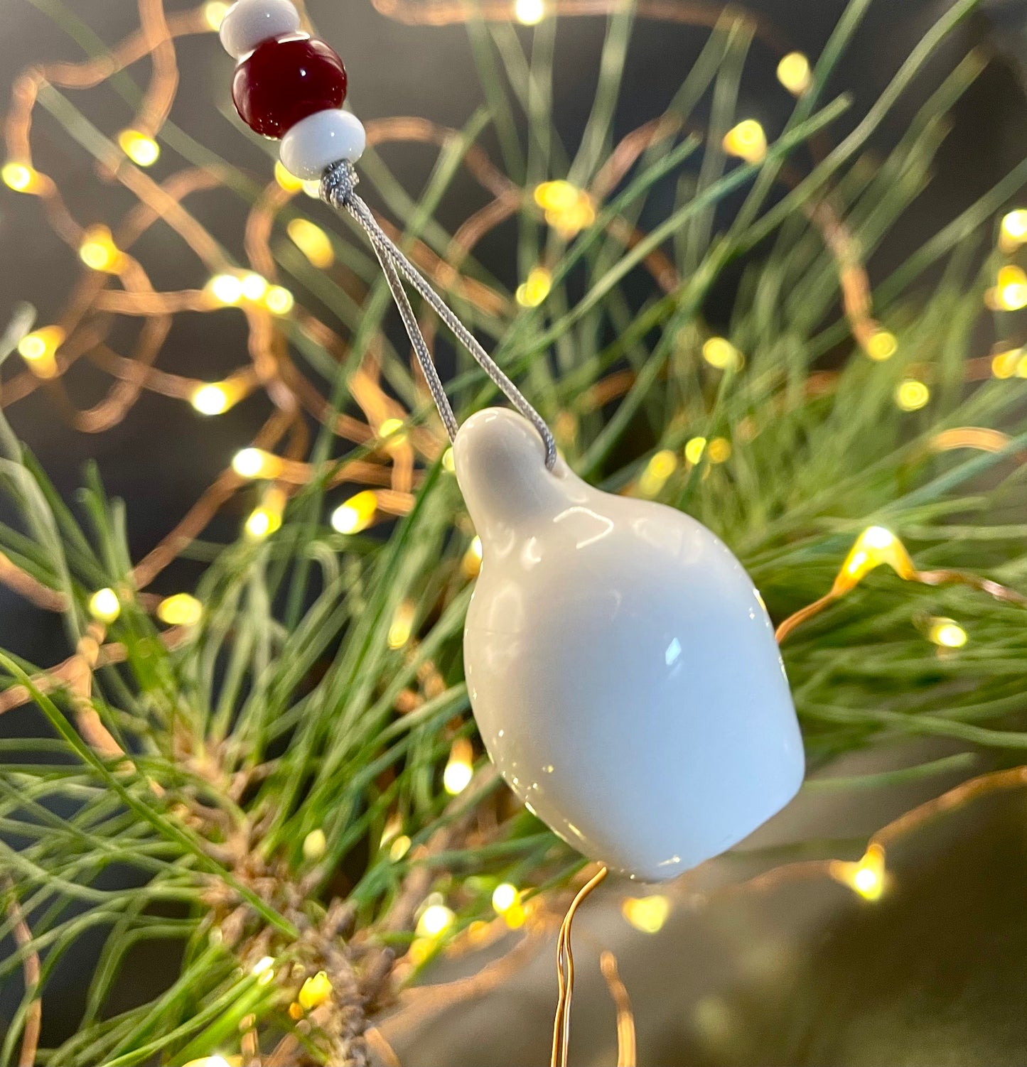 Christmas tree decorated with a single ceramic gumnut ornament, complemented by a red glass bead, highlighting the beauty of handmade decorations and the joy of the holiday season.
