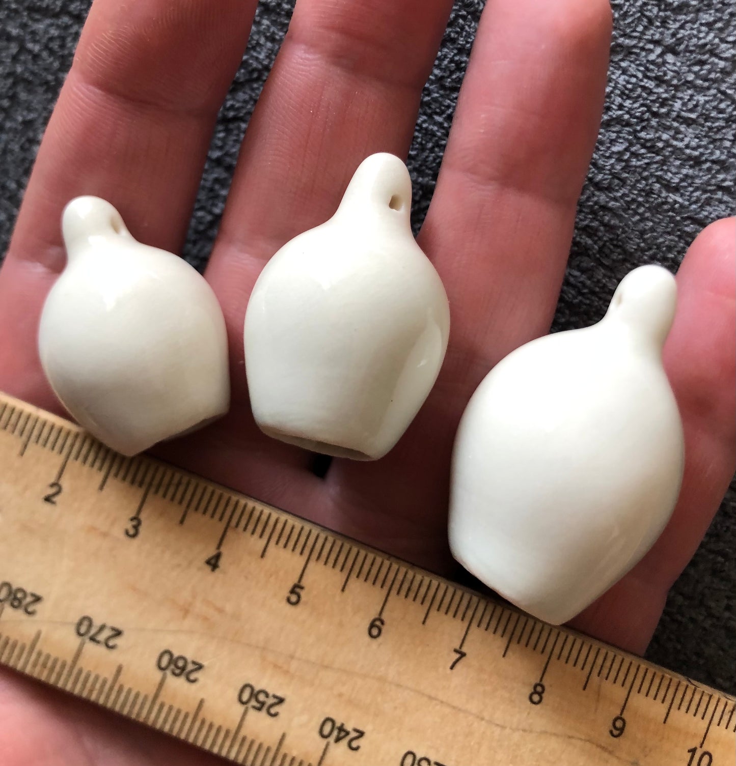 Ceramic gumnuts, typically ranging in size from a few centimetres to several centimetres in diameter, placed alongside a ruler to illustrate their dimensions, showcasing the natural charm and varying sizes of these Australian-inspired decorations.