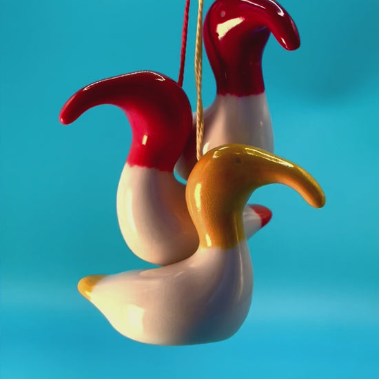 Colourful animation of three Australian White Ibises, or 'bin chickens,' with red and yellow decorations hanging from them, capturing their lively and playful personalities.